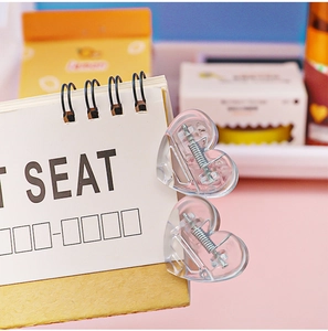 Close-up of heart-shaped transparent plastic clips on a desk calendar for office decor