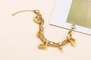 Détail d'un bracelet double couche doré avec cœurs ajourés et billes en métal poli