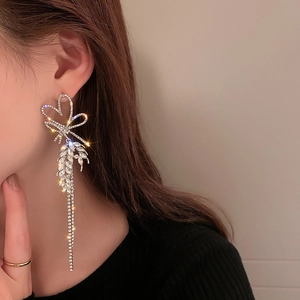 Close-up of sparkling rhinestone tassel earrings with bow design on female model