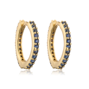 Detailed close-up of golden hoop earrings featuring blue sapphire pavé setting on white