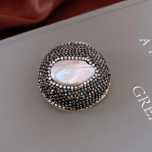 Vue détaillée de la broche perle baroque avec zircons noirs et finition dorée de luxe