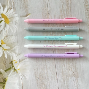 Detailed flat lay of five pastel-colored retractable gel pens on a rustic wood surface