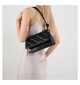 Detail of black crossbody bag featuring geometric triangle quilting and knotted strap