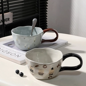 Close-up of ceramic mugs with cute bear and rabbit patterns and stainless steel spoons