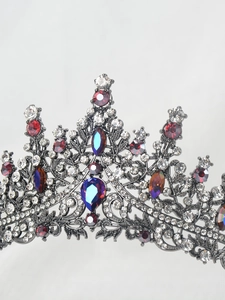Detailed view of silver princess crown with red and blue crystals on white background