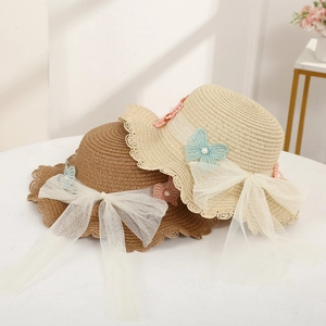 Detailed view of woven straw sun hats featuring large tulle bows and pearl embellishments