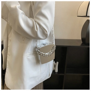 Silver geometric hard shell clutch bag with thick chain handle shown on white suit