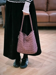 Dettaglio della borsa hobo in tweed viola con trama spessa e tracolla alla moda