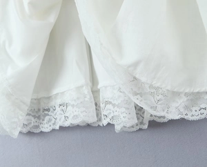 Detailed view of the white mini skirt featuring delicate ruffle lace trim on cotton fabric