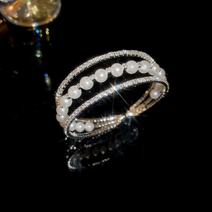 Detailed view of layered silver bracelet with sparkling rhinestones and white pearls