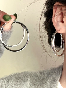 Close-up of double hoop silver earrings featuring one polished and one pavé-set circle