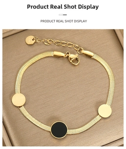 Macro detail of golden stainless steel snake chain bracelet with black enamel charms