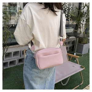 Sac bandoulière en cuir rose avec une large sangle à rayures noires et blanches tendance