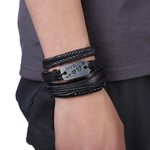 Gros plan d'un ensemble de bracelets en cuir noir avec breloque Love gravée au poignet