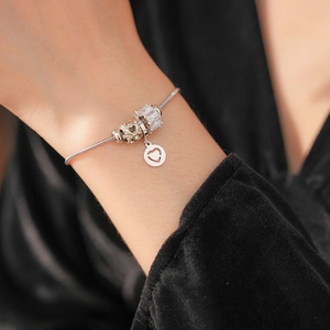 Close-up of a silver snake chain bracelet featuring sparkling heart-shaped charms with pavé crystals