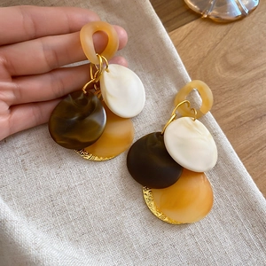 Detail of vintage geometric acrylic tassel earrings with marbled resin layers and gold accents