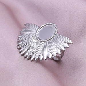 Detailed view of silver sunburst ring with radiant rays on soft purple silk fabric
