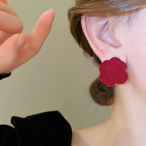 Close-up of elegant red flocked camellia flower earring on female model for autumn winter