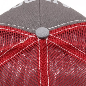 Macro shot of trucker hat crown showing red mesh and grey cotton with white stitching