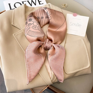 Elegant polka dot silk scarf tied in a bow on a beige blazer for stylish workwear look