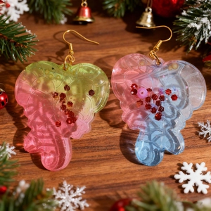 Detail of glitter resin heart candy cane earrings on a festive wooden backdrop