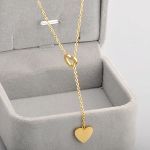 Collana in acciaio dorato con doppio ciondolo a cuore in una scatola grigia