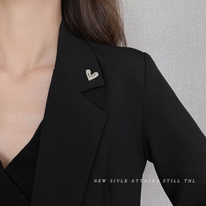 Minimalist gold heart-shaped brooch pin with hollow texture on a black suit lapel