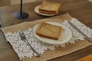 Detailed overhead view of a rustic linen placemat with white lace trim on wood