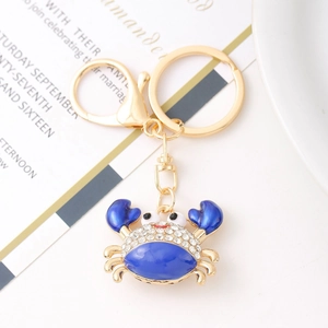 Close-up of golden metal crab keychain with blue enamel and clear rhinestones