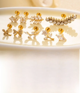 Dettaglio di piercing labret in titanio G23 con fiori in zircone e varie forme di foglie