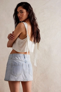 Détail du haut caraco blanc à lacets et de la mini-jupe en jean bleu clair sur mannequin