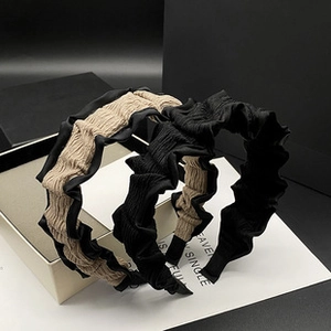 Close-up of pleated satin headbands in black and khaki colors with fabric texture