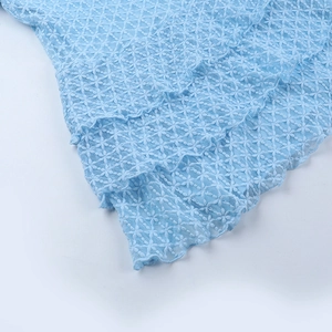 Dettaglio di abito in pizzo azzurro con strati di tulle a balze e ricami floreali