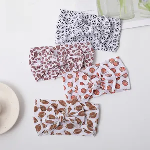 Close-up of four nylon baby headbands with soccer, basketball, and football prints