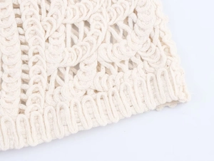 Detailed close-up of cream crochet knit top featuring intricate hollow patterns and wavy edge