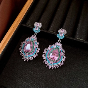 Macro shot of silver earrings with teardrop pink gemstones on black velvet tray
