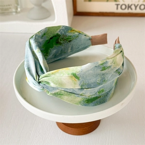 Détail du bandeau en satin aquarelle bleu et vert avec nœud sur plateau de luxe