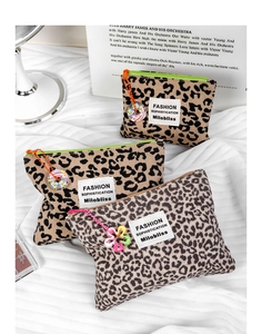 Dettaglio di pochette per trucco in tela leopardata con cerniera e ciondoli decorativi