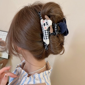 Détail d'une pince à cheveux à carreaux avec une peluche de chien sur une coiffure