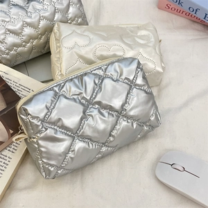 Close-up of quilted heart patterns on silver and beige travel cosmetic bags