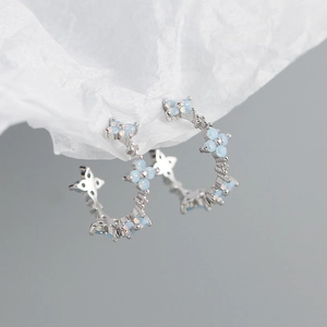 Macro detail of S925 silver C-shape earrings with blue opal-like floral motifs