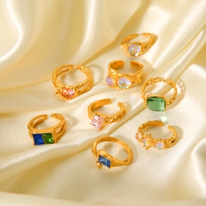 Close-up of vintage gold stainless steel rings with colorful zircon on white silk fabric