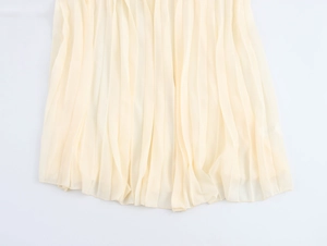 Dettaglio dell'orlo in chiffon a pieghe di un abito francese color crema con scollo a V