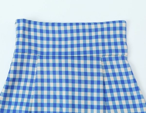 Detail of high-waist blue gingham skirt with side zipper and elegant pleated design