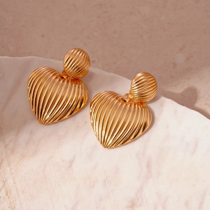 Detail view of gold textured heart earrings featuring elegant vertical stripe patterns