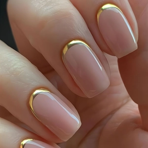 Close-up of nude pink square press-on nails with luxury gold metallic French tips