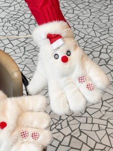 Detail of white faux fur gloves with red knit cuffs and a festive snowman face design