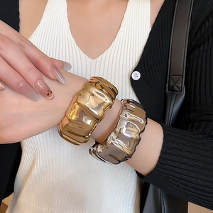 Gros plan de bracelets en métal liquide ondulé en finition or et argent sur un mannequin