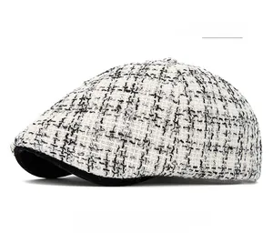 Detailed view of off-white tweed texture and stiff brim on the knit newsboy cap