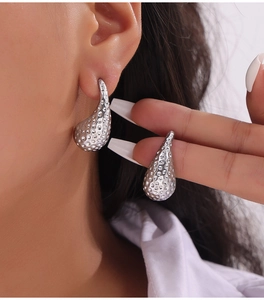 Gros plan d'une boucle d'oreille goutte argentée martelée portée par un mannequin